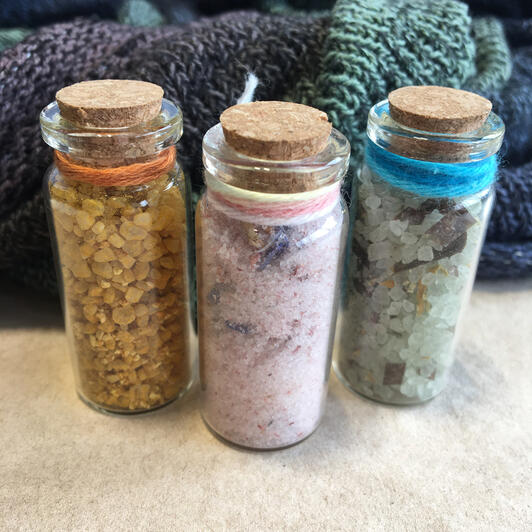 Three small corked bottles with colourful blends of spices in orange, pink, and green